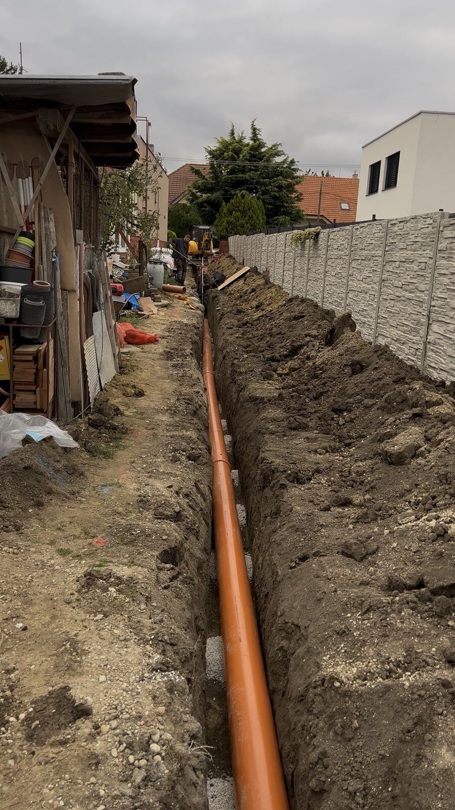 Výkop s uloženou kanalizačnou rúrou pozdĺž plota