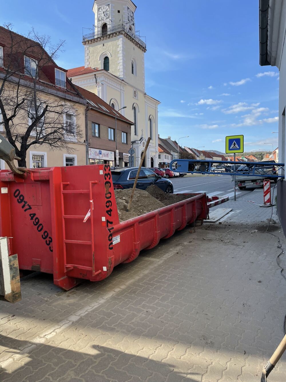 Veľký červený kontajner s telefónnym číslom na námestí v Modre